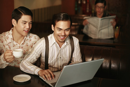 Man using laptop while his friend looks onの写真素材