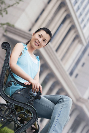 Woman looking away while sitting on a benchの写真素材