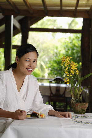 Woman in bathrobe eating saladの写真素材