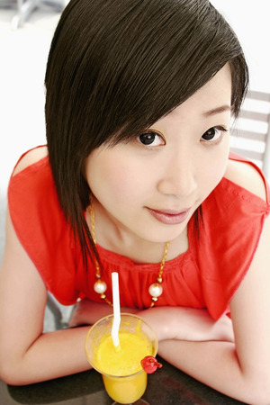 Woman with a glass of orange juice in front of herの写真素材