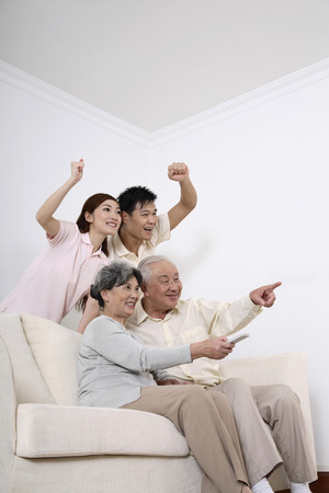 Happy family cheering while watching television togetherの写真素材