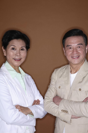 Senior man and senior woman posing with their arms foldedの写真素材