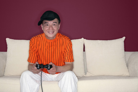 Senior man with cap playing video game console