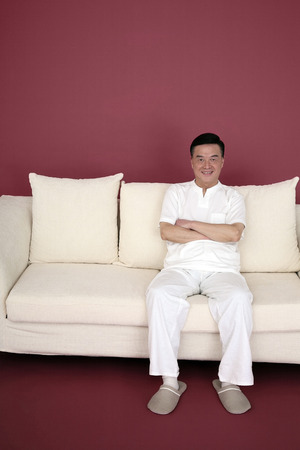 Senior man sitting on the couch, arms foldedの写真素材