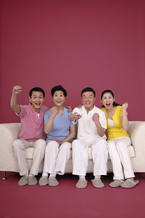 Family cheering while watching televisionの写真素材