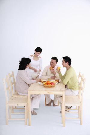 Woman pouring milk for senior woman, man and senior man watchingの写真素材