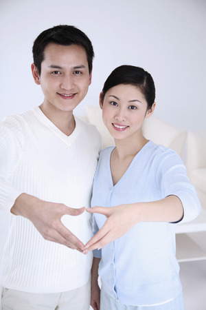 Man and woman forming heart shape with fingersの写真素材