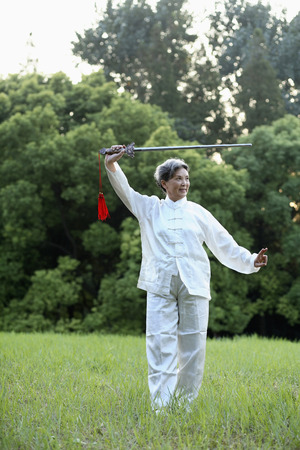 Woman practising Tai Chi with swordの写真素材