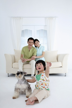 Girl posing with dog, parents watchingの写真素材