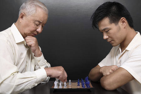Senior man and man playing chess gameの写真素材