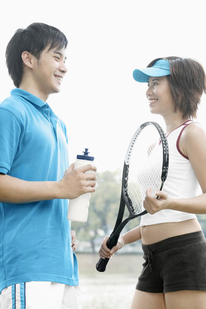 Woman with tennis racquet talking to manの写真素材
