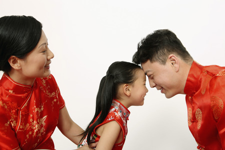 Girl and man smiling with foreheads together, woman watchingの写真素材