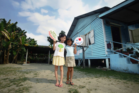 Children holding placards displaying 'We love Malaysia' and 'Happy Birthday Malaysia'の写真素材