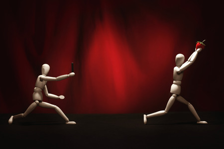 Wooden dummy chasing after another wooden dummy with strawberryの写真素材