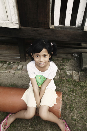Girl sitting on pipe, smilingの写真素材