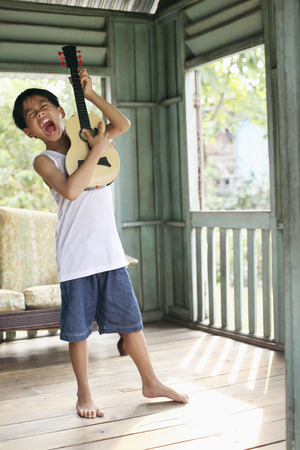 Boy singing while playing guitarの写真素材