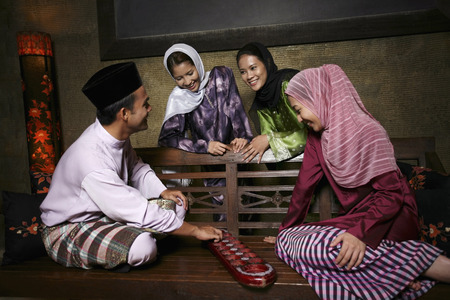 Man and woman playing congkak, the rest watchingの写真素材