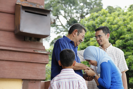 Woman greeting senior man, man and boy watchingの写真素材