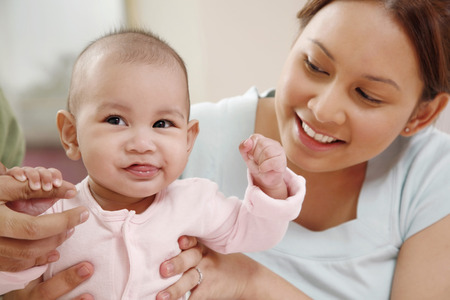 Baby sticking out her tongue, woman watching
