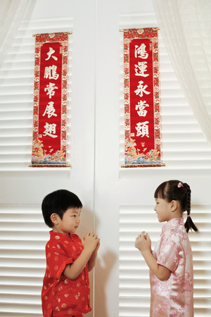 Boy and girl in traditional clothing greeting each otherの写真素材