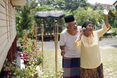 Senior woman talking on the phone, senior man smilingの写真素材