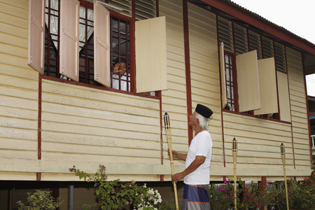 Boy waving to senior man from the house windowの写真素材