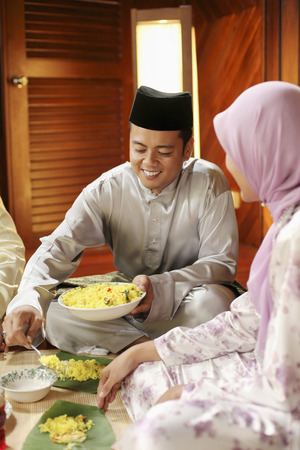 Man scooping nasi briyani onto banana leafの写真素材