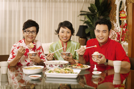 Man and woman having lunch together with senior woman at the dining tableの写真素材