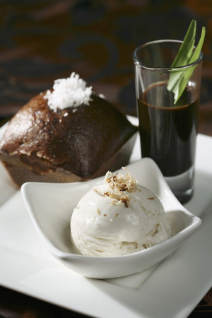 Steamed palm sugar sponge cake served with a shot of caramelized palm sugar and a scoop of coconut ice-creamの写真素材