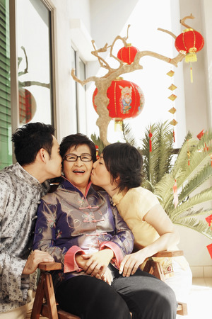 Man and woman giving senior woman a peck on her cheekの写真素材