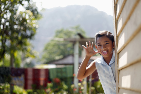 Girl standing at the side of the house, making face and hand gesture