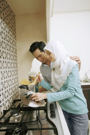 Woman preparing spaghetti, man watching herの写真素材