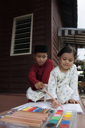Girl colouring her book, boy watching and pointingの写真素材