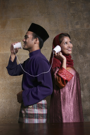 Man and woman communicating through tin can telephoneの写真素材