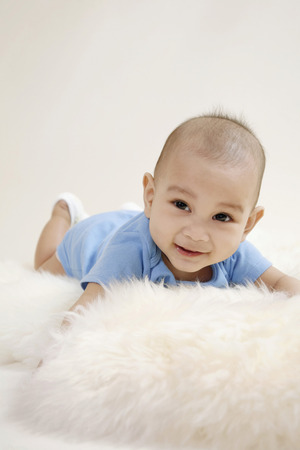 Baby lying forward on furの写真素材