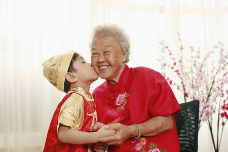 Boy kissing senior woman on the cheek after receiving a red packetの写真素材