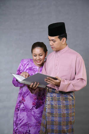 Man and woman in traditional clothing reading documentの写真素材