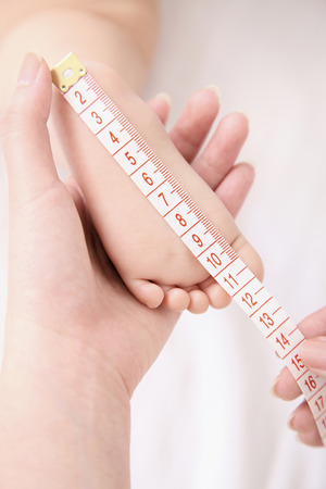 Woman measuring foot of babyの写真素材