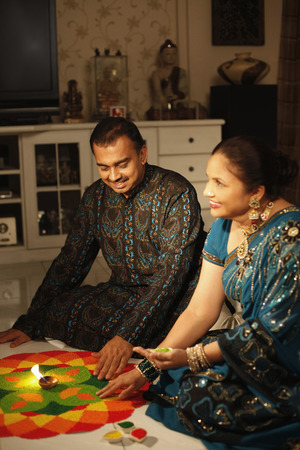 Man and woman drawing kolam on the floorの写真素材