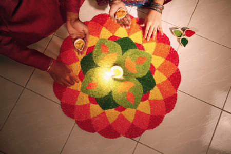 Teenage girl and young man drawing kolam on the floorの写真素材