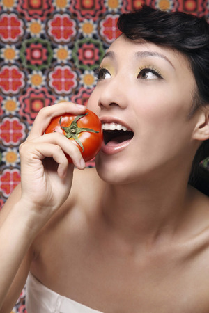 Woman about to eat tomatoの写真素材