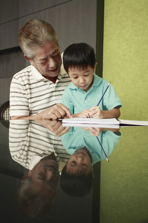 Boy doing homework, man watchingの写真素材