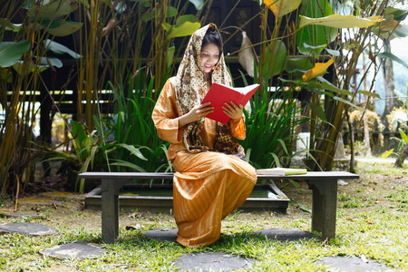 Woman in traditional clothing reading book in the house compoundの写真素材