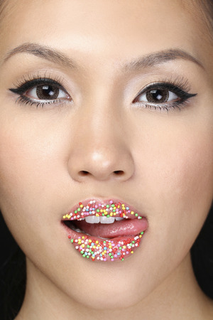 Woman licking candy sprinkles on lipsの写真素材