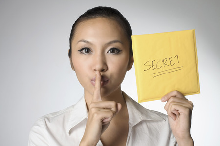 Businesswoman gesturing while holding paper with the word 'Secret'の写真素材