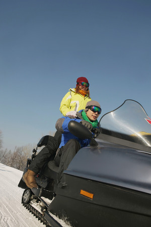 Man and woman riding on snowmobileの写真素材