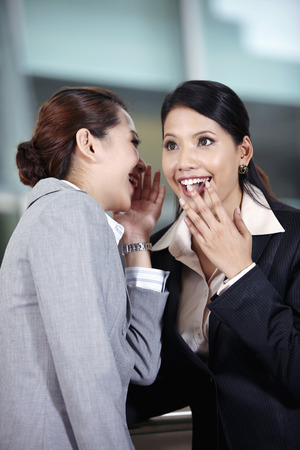 Businesswomen whispering to each otherの写真素材