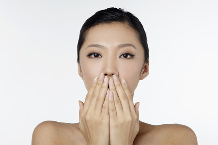 Woman with hands over her mouthの写真素材