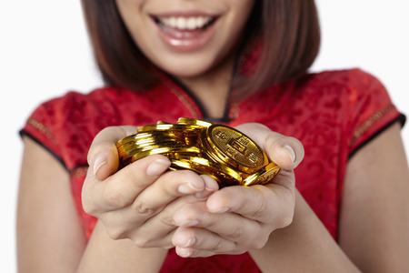 Woman in traditional clothing holding a handful of Chinese golden coinsの写真素材