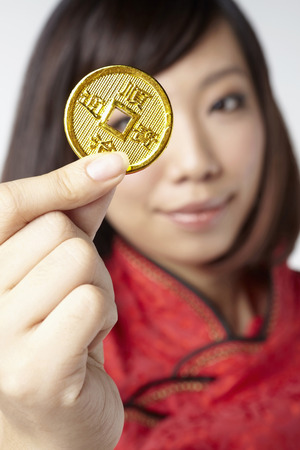 Woman in traditional clothing holding a Chinese golden coinの写真素材